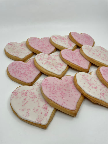 One Dozen heart shaped sugar cookies.  Half iced with white and the other with pink icing.  All sprinkled with pink sanding sugar.